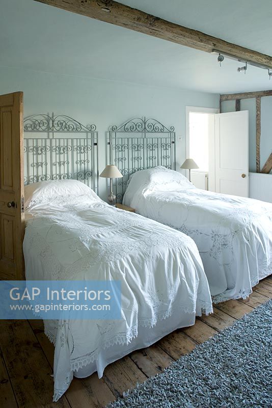 Ferme Boonshill, East Sussex. Intérieur de la chambre d'amis avec couvre-lits en dentelle antique et portes métalliques comme têtes de lit.