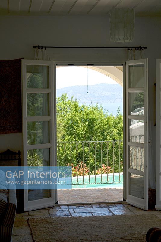 Corfou, Grèce. Yialiskari House Villa près de Kalami. Vue à travers le salon sur la piscine et les montagnes albanaises