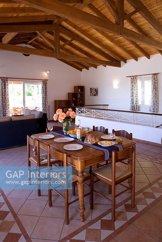 Villa Christina, Kaminaki, Corfou, Grèce. Salon et salle à manger à aire ouverte avec table et sol carrelé en pierre