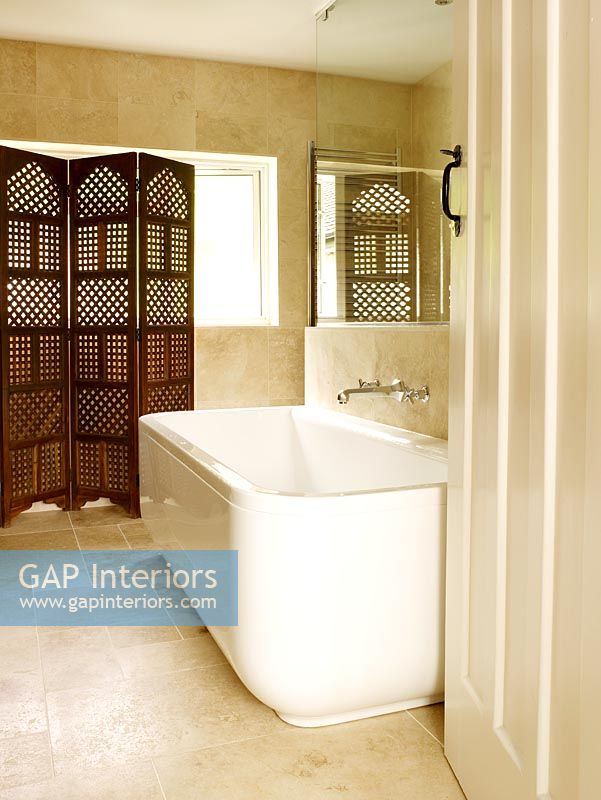 Salle de bain moderne avec baignoire, grands carreaux de grès et paravent en bois