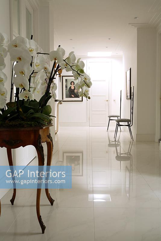 Couloir blanc classique avec table console et sol en marbre