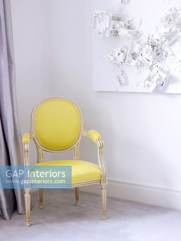 Salon avec chaise jaune rembourrée classique et art abstrait sur le mur