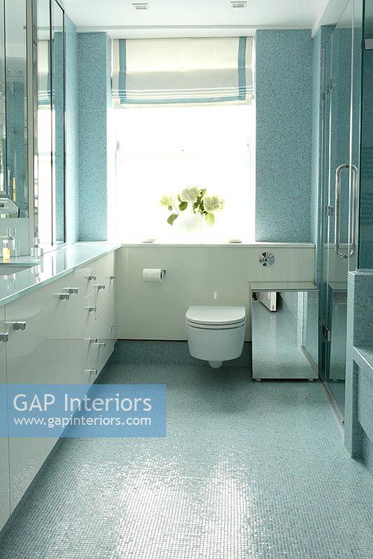 Salle de bain moderne avec rangement intégré et murs et sol en mosaïque bleue