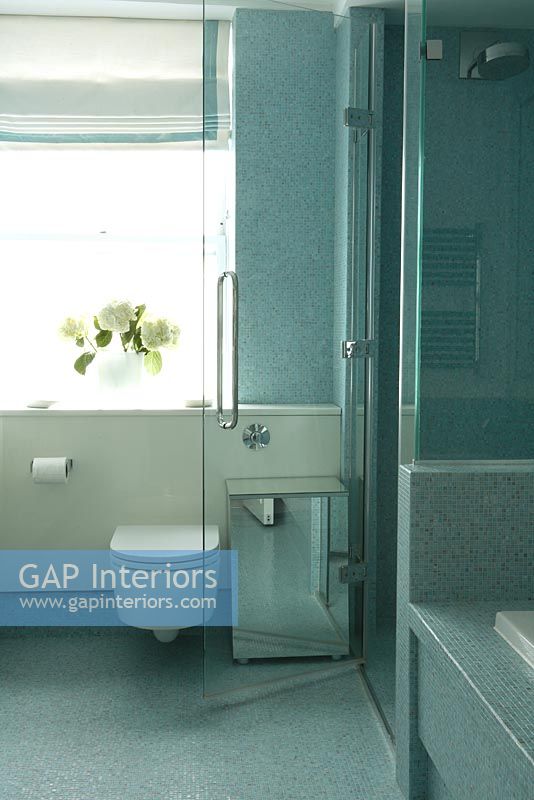 Salle de bain moderne avec cabine de douche et baignoire séparées et murs et sol en mosaïque bleue