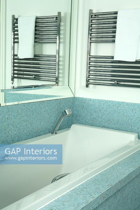 Salle de bain moderne avec des carreaux de mosaïque bleue et une serviette suspendue à un radiateur sèche-serviettes