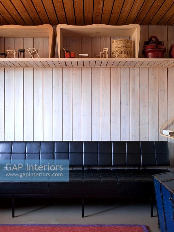 Salon de style scandinave avec canapé en cuir et murs lambrissés