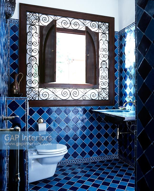 Salle de bain originale avec des carreaux bleus et une grande armoire ornée