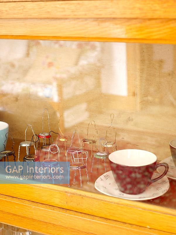 Détail de vitrine en verre avec des tasses et des petites chaises femme de chambre du haut des bouteilles