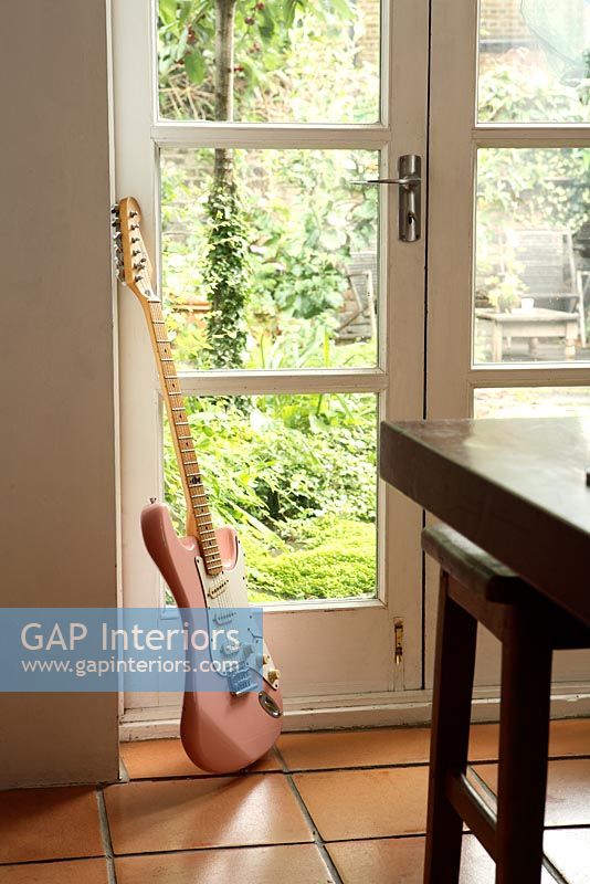 Détail des portes françaises dans la cuisine avec guitare reposant contre le mur