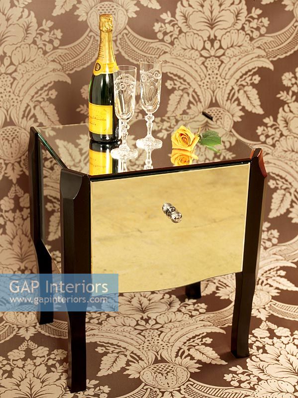 Champagne et verres sur une table devant un papier peint orné
