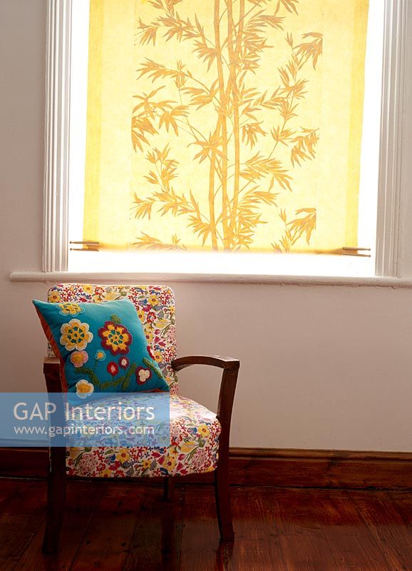 Fauteuil à motifs floraux devant la fenêtre avec store jaune