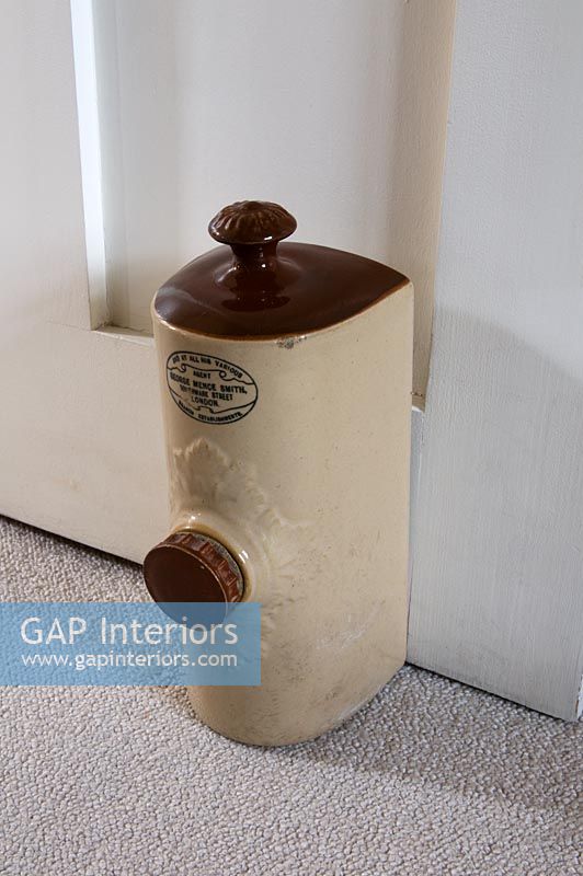 Bouteille d'eau chaude victorienne utilisée comme butoir de porte