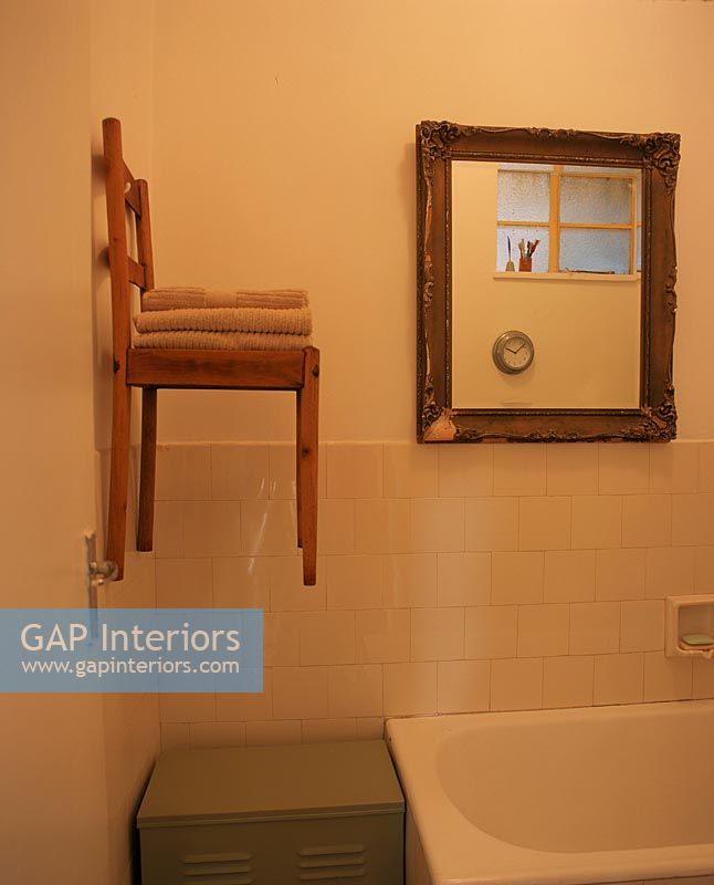 Salle de bain avec une chaise accrochée au mur utilisée comme étagère pour les serviettes