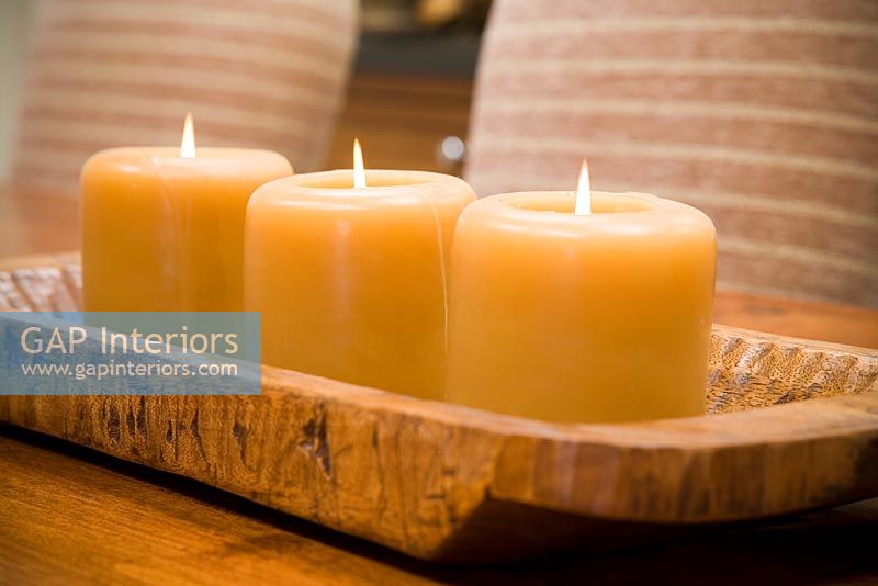 Détail de trois bougies allumées sur support en bois.