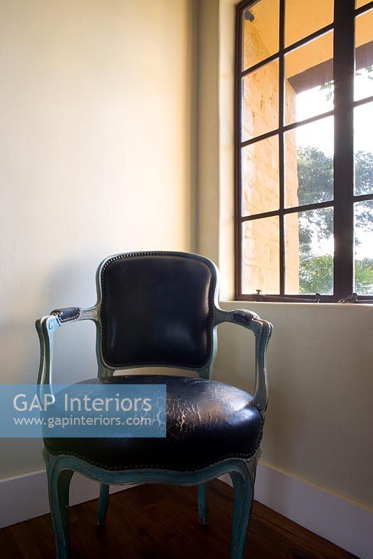 Chaise en cuir antique usée dans un coin à côté de la fenêtre
