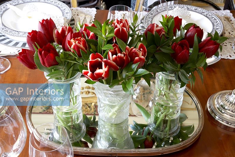 Détail de la table à manger de trois vases en verre taillé avec des tulipes rouges