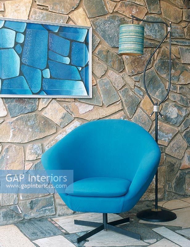 Salon aux murs en pierre avec fauteuil bleu