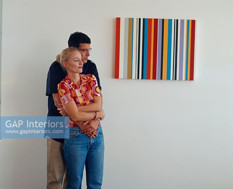 Homme tenant une femme à côté d'une peinture moderne