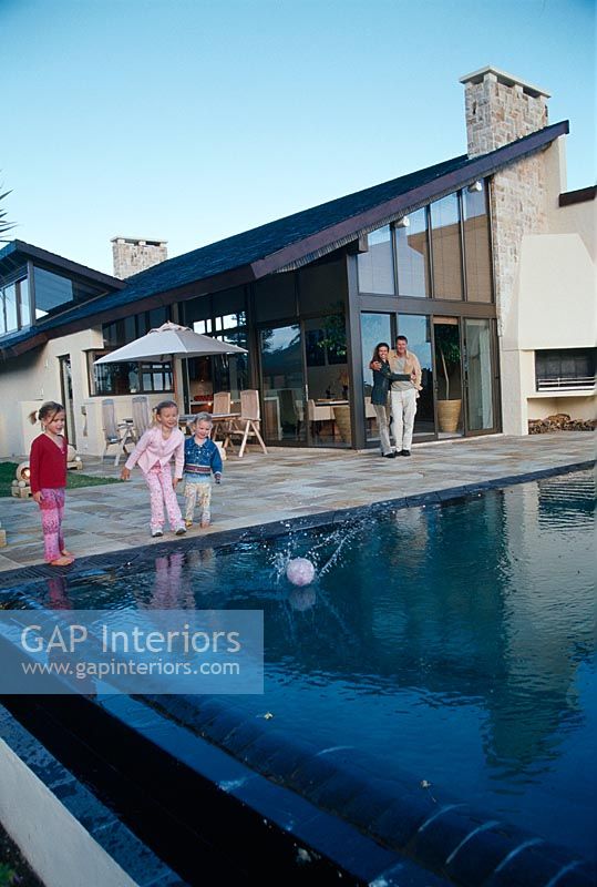 Famille jouant avec un ballon près d'une piscine