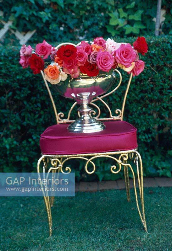 Roses en urne argentée sur une chaise rouge