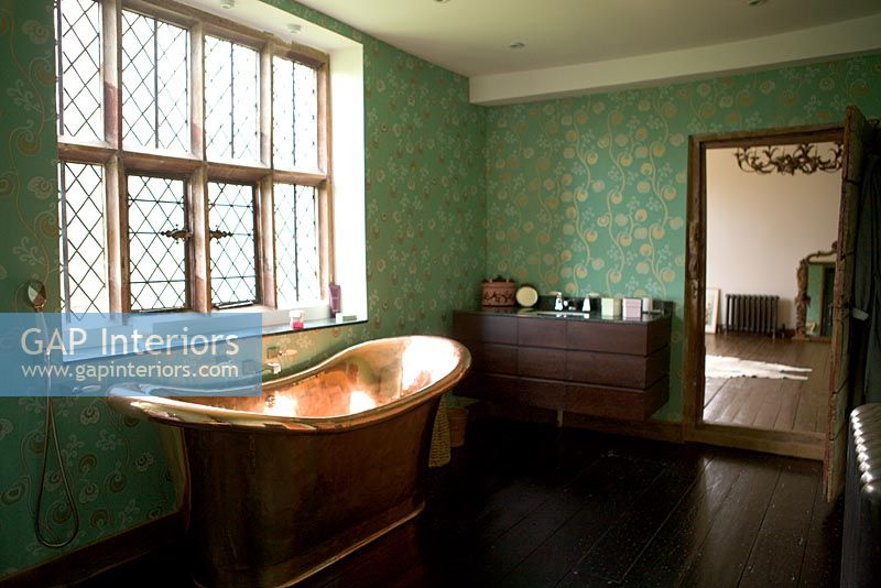 Bain en cuivre à côté de la fenêtre à carreaux de plomb dans la salle de bain traditionnelle