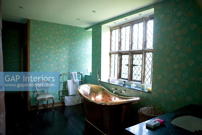 Bain en cuivre sous fenêtre à carreaux de plomb dans la salle de bain traditionnelle