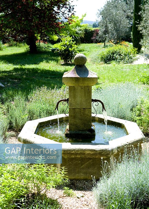 Puits d'eau en pierre traditionnelle dans un jardin de campagne