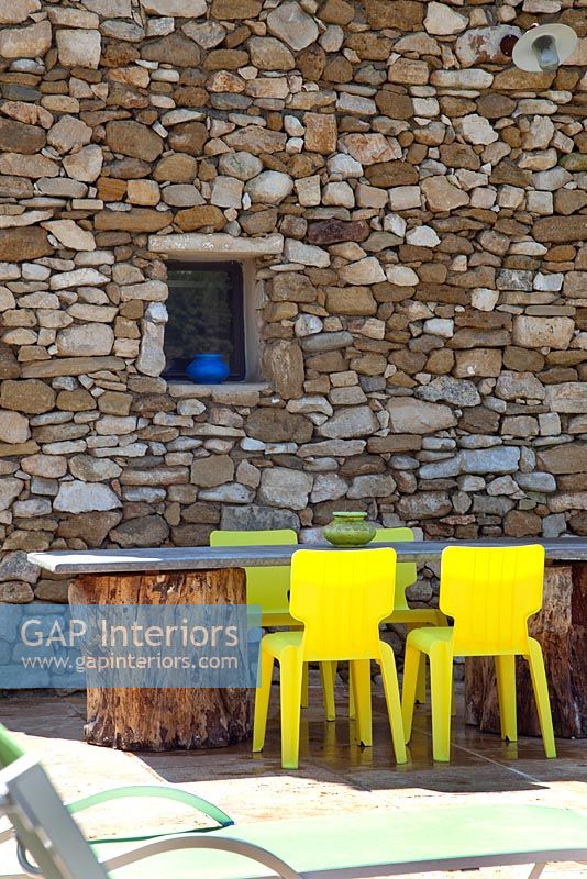 Table et chaises de jardin par mur de pierre rustique