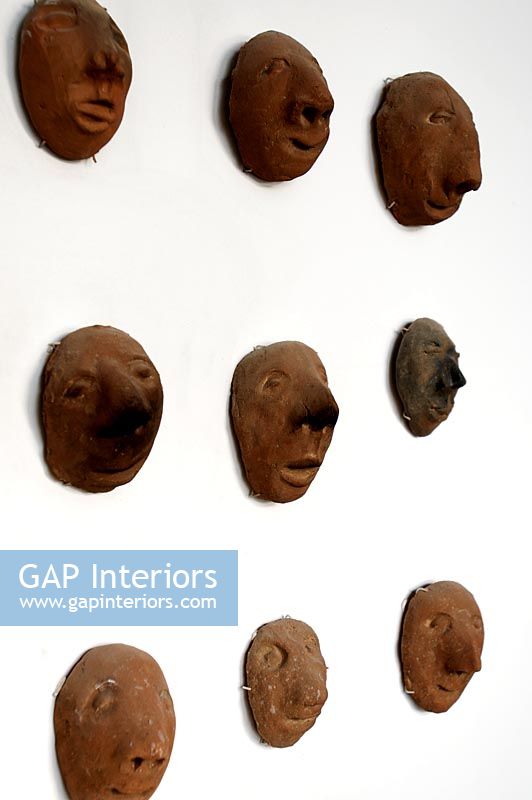 Collection de têtes d'argile sur mur, détail