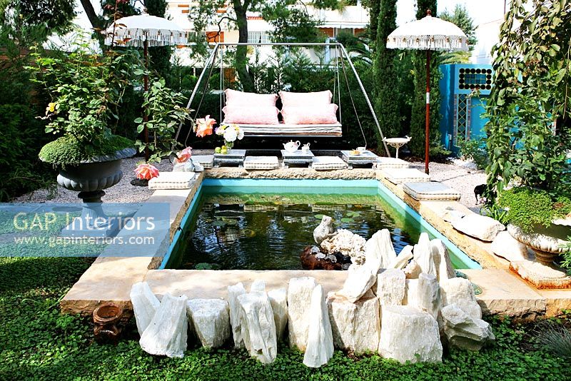 Siège de balançoire par étang dans un jardin moderne