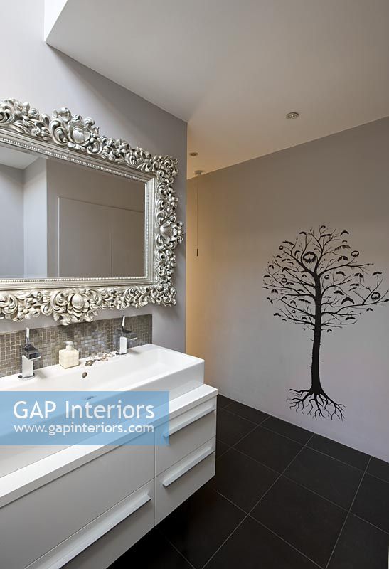 Évier, miroir orné et papier peint mural arbre dans la salle de bain
