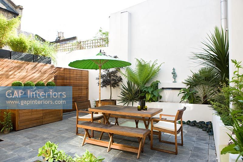 Jardin patio contemporain avec mobilier en bois et parasol vert