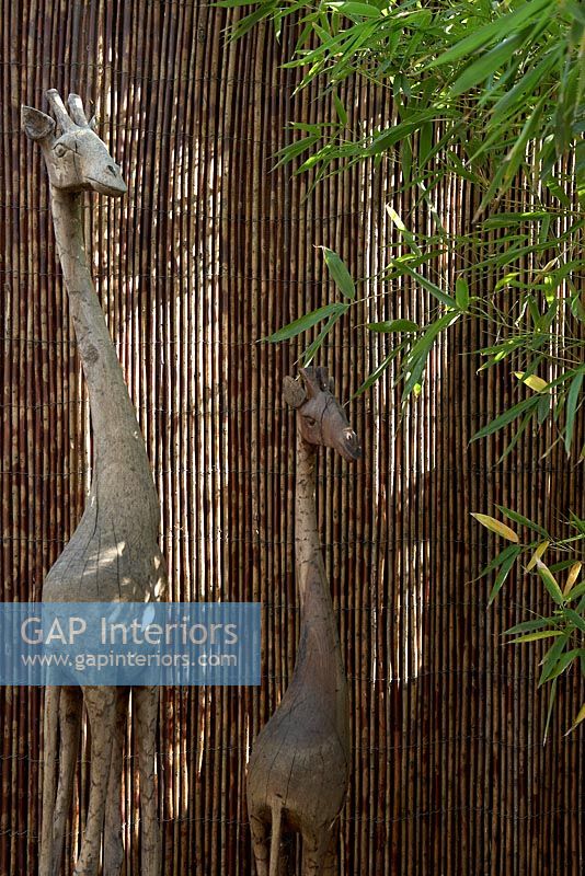 Sculptures de girafe en bois par clôture en bambou