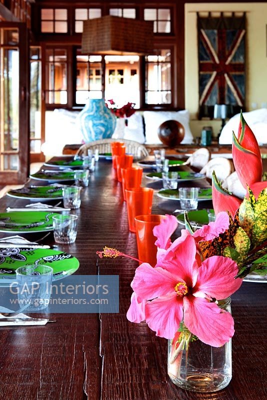 Fleurs tropicales sur une longue table à manger en bois pour le repas