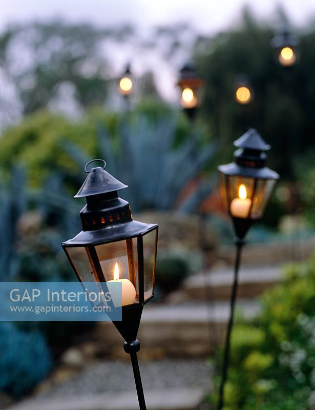 Lanternes avec des bougies allumées dans le jardin