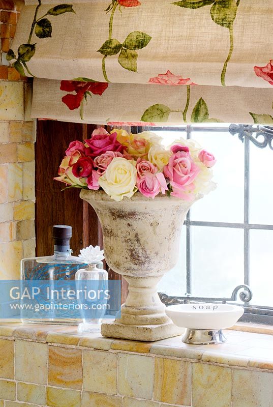 Vase en pierre de fleurs sur le rebord de la fenêtre de la salle de bain