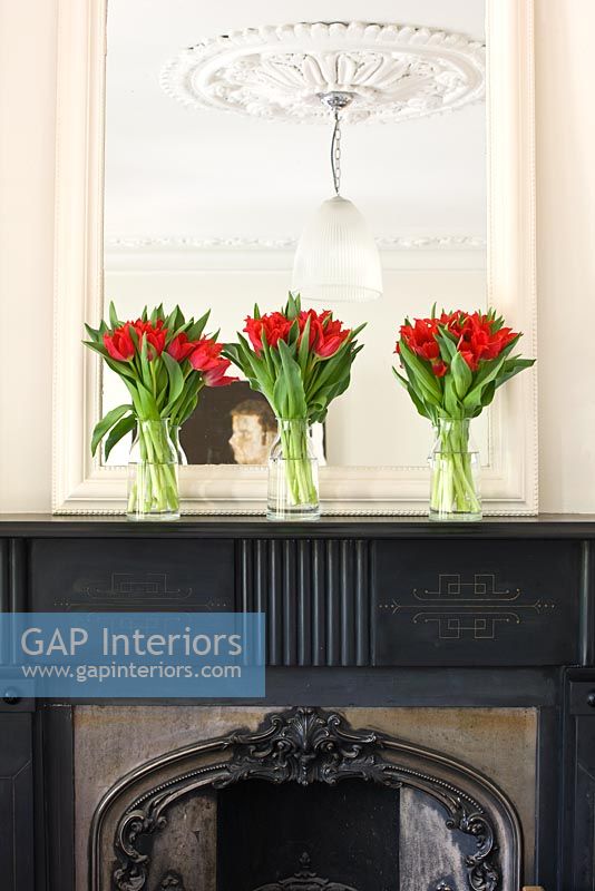 trois vases de tulipes rouges sur le manteau