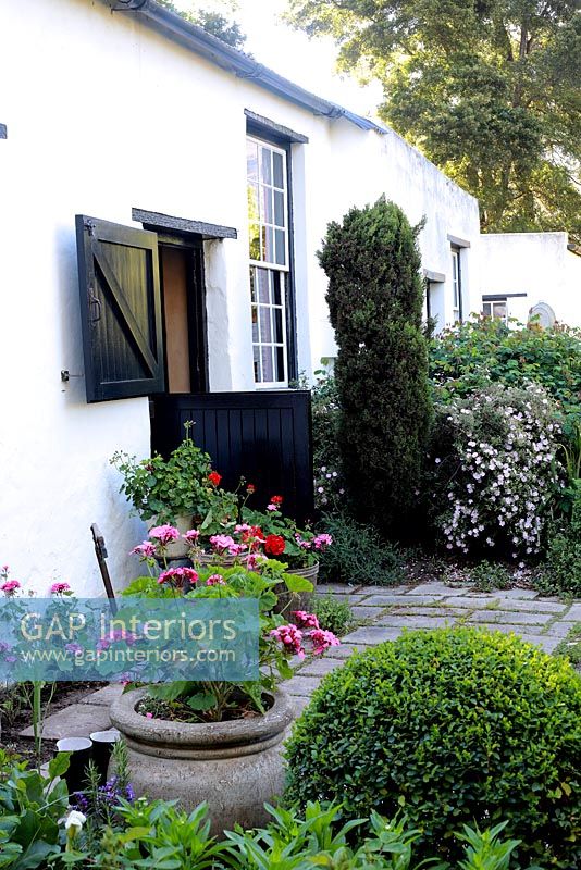 Cottage avec porte d'écurie et pots de géraniums