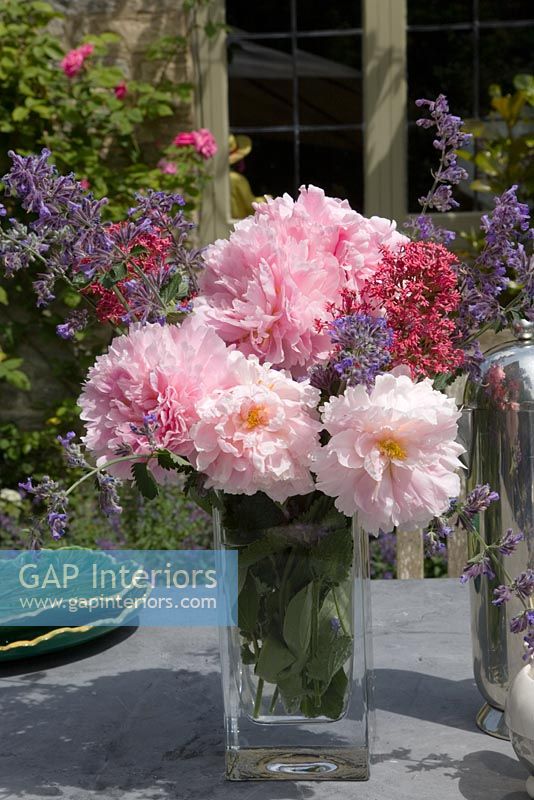 Arrangement de roses, menthe et valériane sur table de jardin