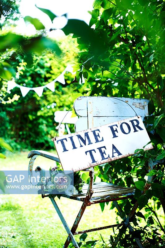 Temps pour le thé signe sur chaise de jardin