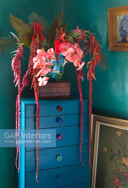 Armoire turquoise avec fausses fleurs en pot de majolique