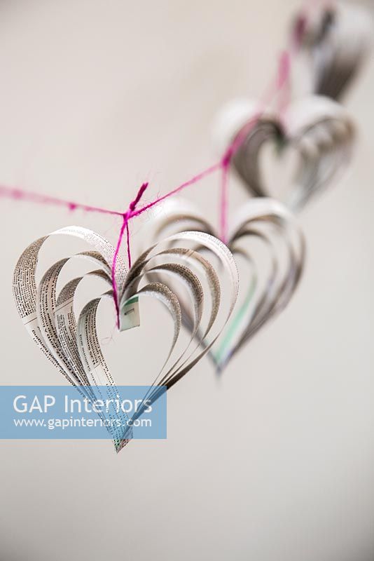 Création d'une décoration en forme de coeur en utilisant du papier journal et du fil coloré - coeurs finis