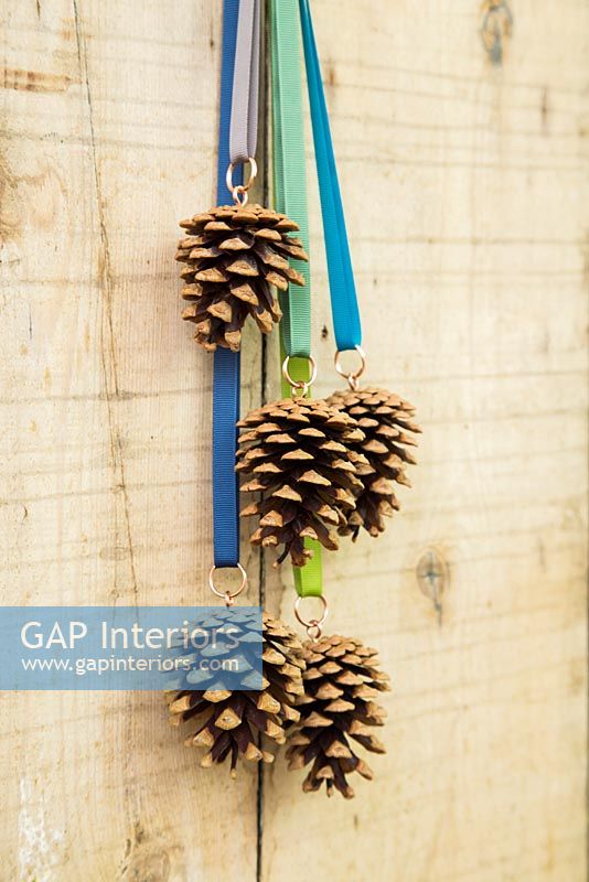 Décorations de Noël faites avec des pommes de pin et un ruban suspendu à une porte en bois