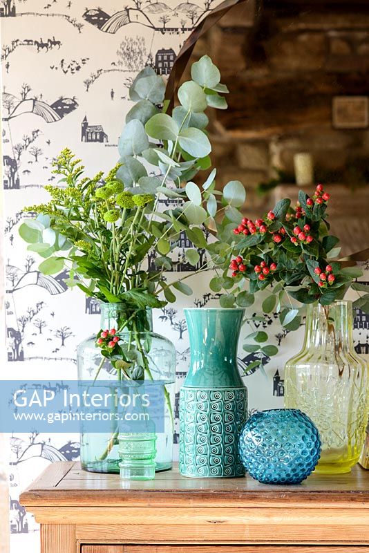 Arrangements de feuillage et de baies dans des vases colorés