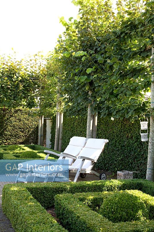 Jardin de parterre formel avec chaises longues blanches