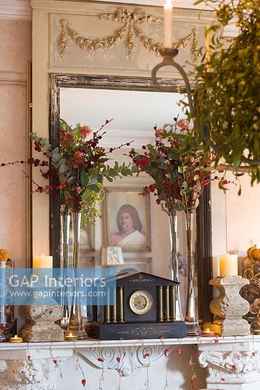 Cheminée ornée avec miroir français, chandeliers en pierre et décorations florales de Noël
