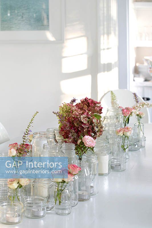 Affichage floral avec des roses et des hortensias sur une table à manger blanche