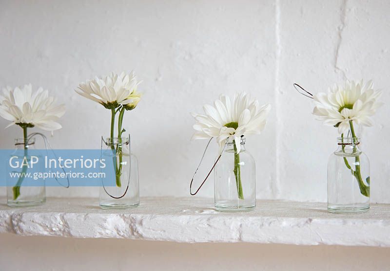 Fleurs blanches dans des bouteilles en verre
