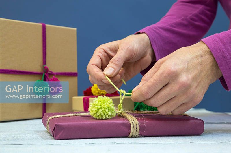 Faire des décorations de pompons de Noël - Fixer un pompon en laine à un cadeau de Noël
