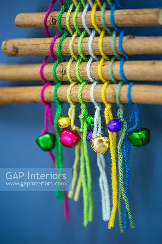 Un arbre de Noël coloré fait avec des bâtons de laine colorée et des boules miniatures sur un fond bleu